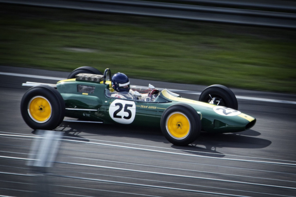 lotus f1 car number 25 in british racing green with yellow wheels racing down a speedway