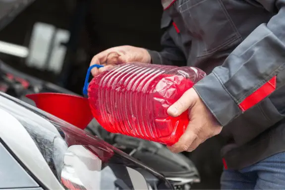 large clear jug of automatic transmission fluid being poured into transmission